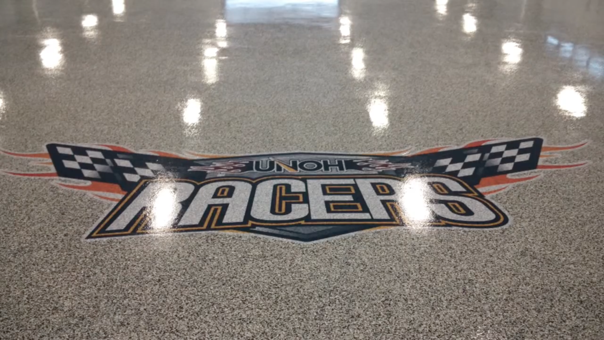 UNOH Racers Logo Epoxy Flake Floor Epoxy flake floor with UNOH Racers logo installed by The Concrete Protector.